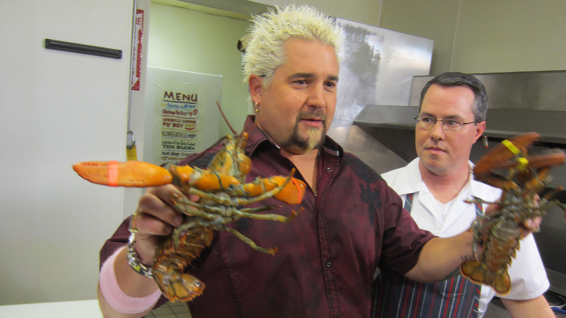 Guy Fieri from Diners, Drive-Ins and Dives holding lobsters and Smack Shack owner Josh Thoma in a commercial kitchen